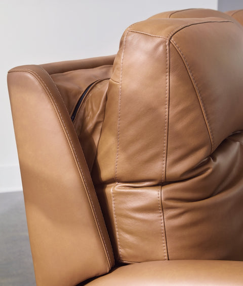Close-up of a brown leather armchair with visible stitching on a light gray background